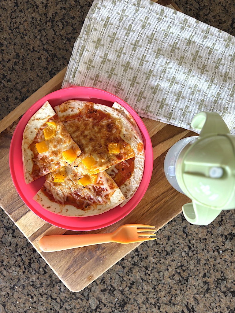 Flat-lay of a air fryer veggie tortilla pizza on a child's plate