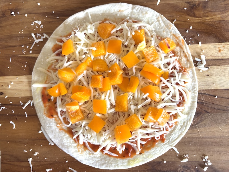 Step 3 of making the tortilla pizza is to add the toppings