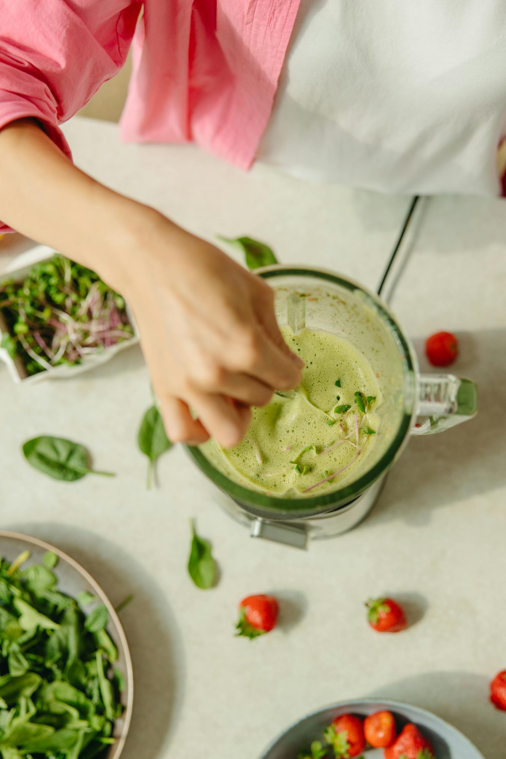 Overhead view of a healthy green smoothie preparation with fresh ingredients.