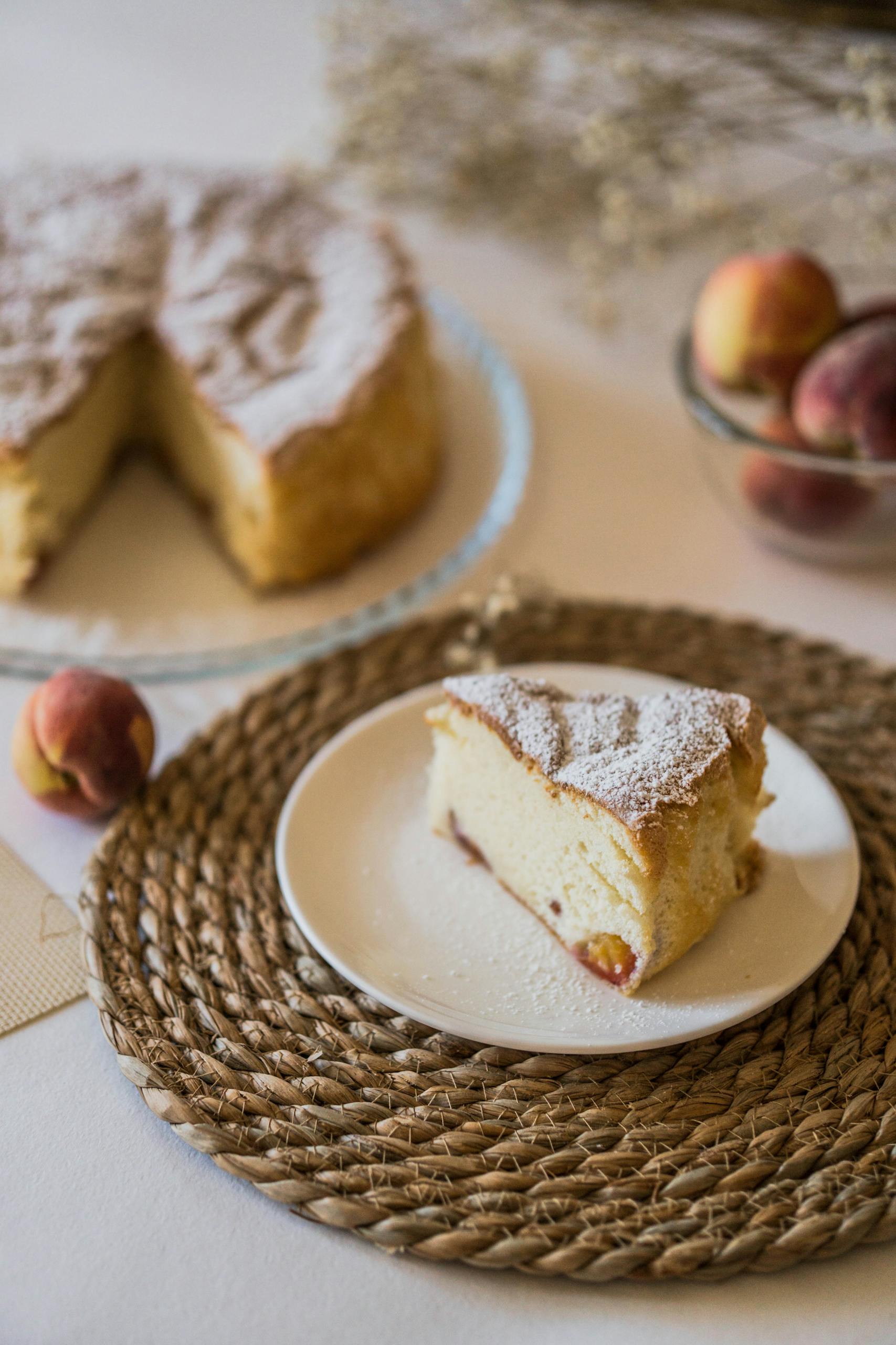A delightful slice of homemade peach cake served on a plate with whole peaches nearby.