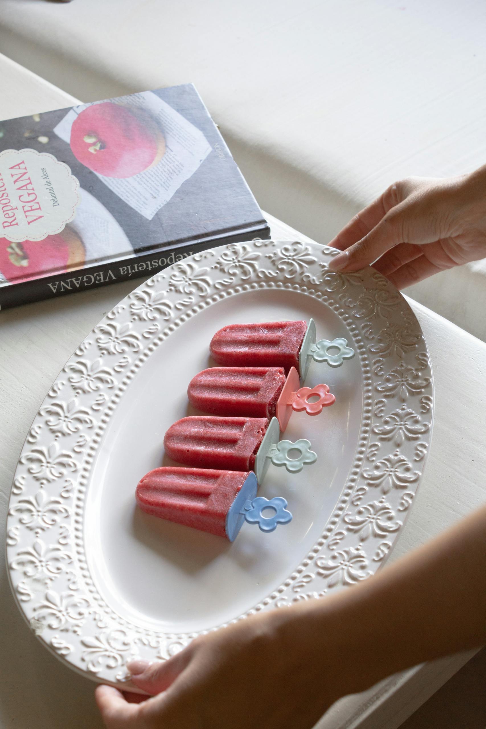 Delicious berry popsicles served on an elegant white decorative plate.