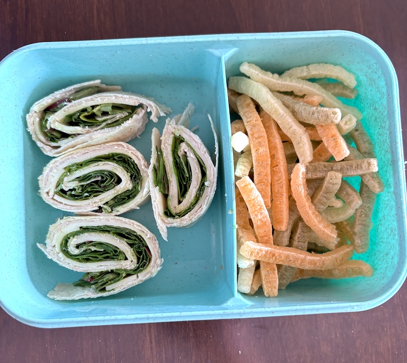 flat lay of lunchbox with spinach turkey cream cheese pinwheel rollups and a side of veggie straws