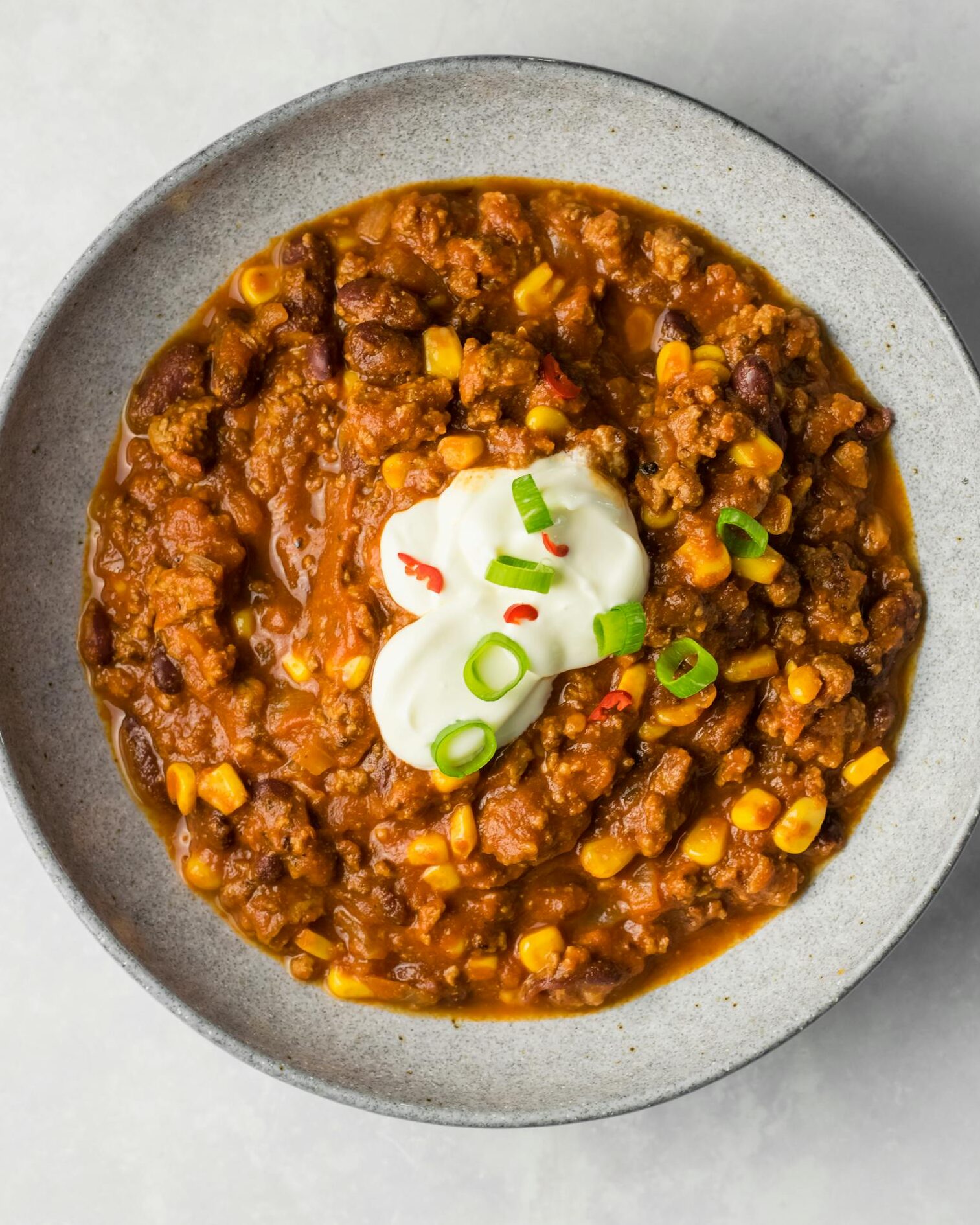 Delicious chili con carne with beans, corn, and sour cream garnish, perfect for dinner.