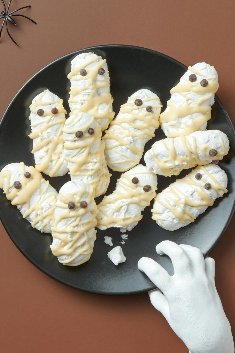 Creepy Halloween-themed sweets arranged with toy spiders and a fake hand. Perfect for festive occasions.