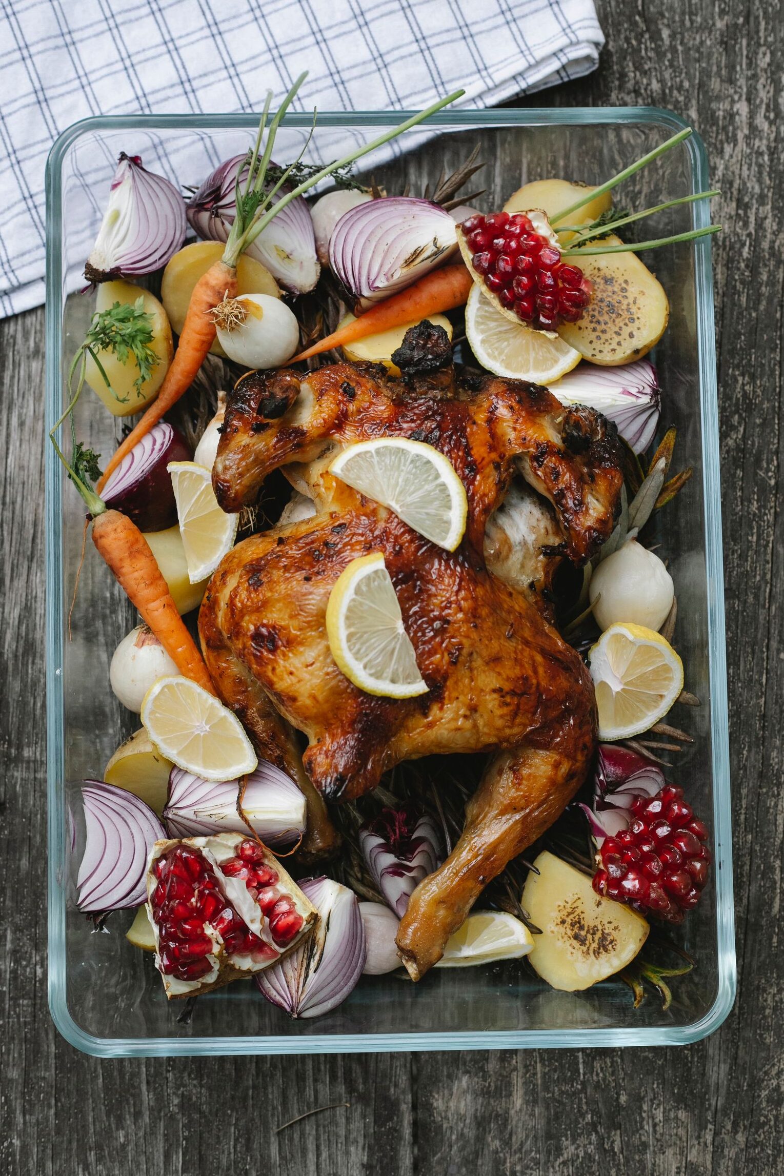 Top view of glass baking dish with yummy roasted chicken and lemon slices with potatoes and carrots